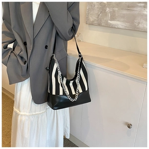 Detail of hobo shoulder bag featuring black and white stripes with a silver chain strap