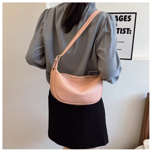 Detail of pink lychee leather saddle bag with adjustable strap worn by a model