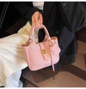 Detailed shot of pink pebble leather tote bag with gold lock and cute bear charm