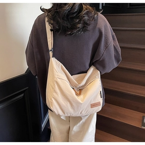 Rear view of a model wearing the large cream canvas messenger bag with adjustable strap