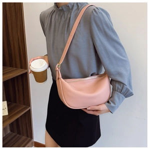 Close-up of pink litchi grain leather texture on a minimalist crescent crossbody bag