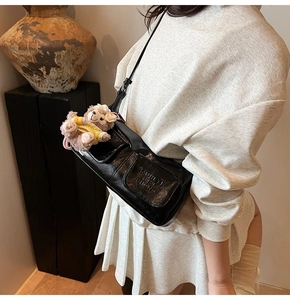 Detail of black pleated faux leather shoulder bag with two front pockets and plush bear charm