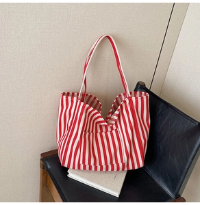 Detailed macro view of large red striped canvas tote bag with front pocket on chair