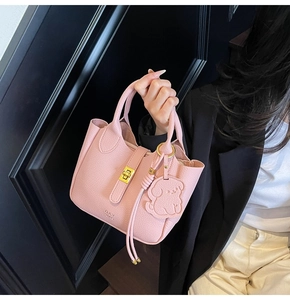 Pink lychee texture handbag featuring gold clasp, dog charm and DAY BAG logo detail