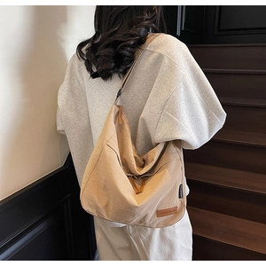 Detail of adjustable strap and khaki canvas material on a large crossbody messenger bag
