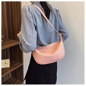 Detail of pink pebbled leather crescent bag with silver zipper and adjustable strap
