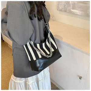 Detail view of black and white striped tote bag with silver chain strap on model