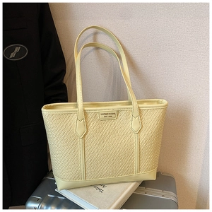 Gros plan de la texture tressée et du logo d'un grand sac cabas jaune de bureau
