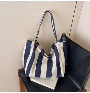 Blue and white striped canvas tote bag detail on a leather chair with props