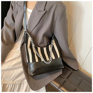 Close-up of black and white striped shoulder bag with bold silver chain and leather strap