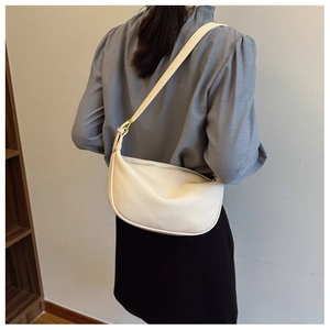 Detail of white crescent bag showing pebbled leather texture and adjustable gold hardware