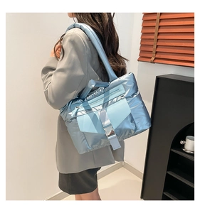 Dettaglio della borsa shopper trapuntata blu metallizzato con tasca a fibbia e zip