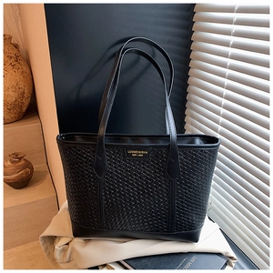 Détail de la texture tressée du sac cabas noir et des finitions en cuir lisse chic