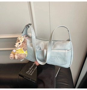 Detail of light blue wrinkled faux leather bag with metallic finish and bear charm