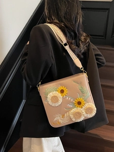 Pastel pink embroidered crossbody bucket bag with floral pattern and woven strap