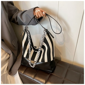 Detail of striped tote bag with black faux leather trim and silver metal chain strap