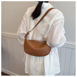Detailed view of brown lychee texture leather saddle bag with adjustable strap and gold zip