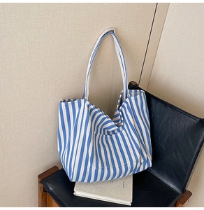 Detail of blue and white striped canvas tote bag with front pocket on a black chair