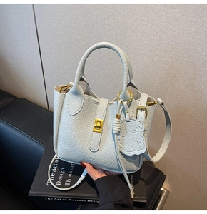 Detail of light blue pebble leather handbag with gold twist lock and dog-shaped tag