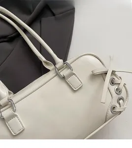 Dettaglio borsa in pelle crema con occhielli in metallo argentato e lacci laterali
