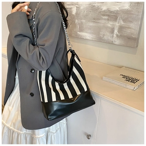 Detail of black and white striped canvas bag with leather base and silver chain strap