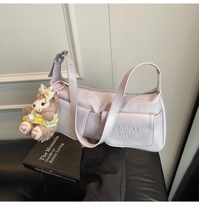 Detail view of lavender faux leather bag with pleated texture and bear plush pendant