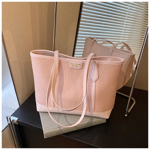 Détail d'un sac cabas rose à texture tressée avec logo et doubles bandoulières