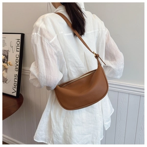 Detail of a brown lychee pattern leather crescent tote bag worn over the shoulder