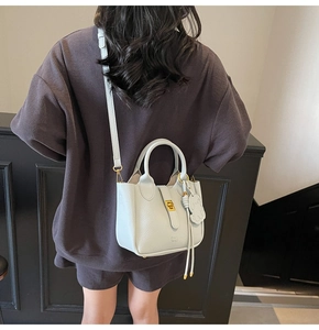 Detail view of light blue leather tote bag with gold lock and dog charm shown on model