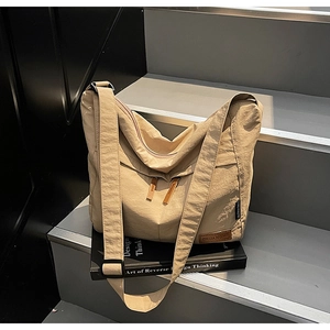 Detail of beige pleated canvas tote bag showing the texture and black adjustable buckle