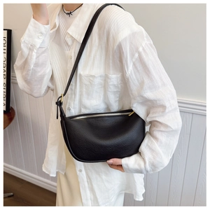 Close-up of black grainy leather saddle bag with silver zipper and adjustable strap