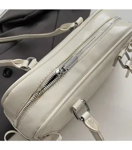 Dettaglio della cerniera argentata e degli inserti metallici sulla borsa beige
