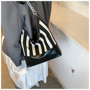 Detail of striped shoulder bag featuring silver chain strap and leather bottom