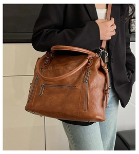 Detail of vintage brown PU leather handbag featuring multiple functional zipper pockets
