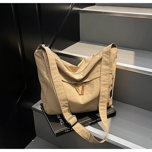 Close-up of adjustable strap and side woven label on beige large canvas messenger bag