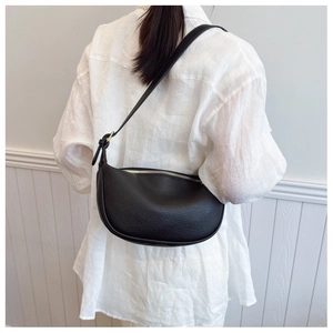Close-up of black lychee texture leather saddle bag with gold zipper detail