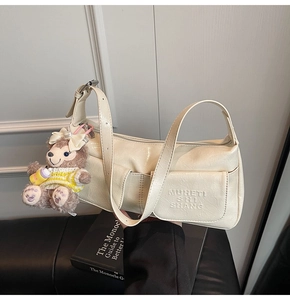Detailed view of cream wrinkled leather shoulder bag with a cute plush bear pendant accessory