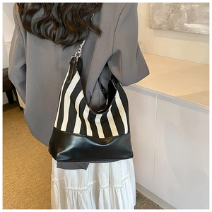 Detail view of the striped hobo bag with silver chain strap on a model's shoulder