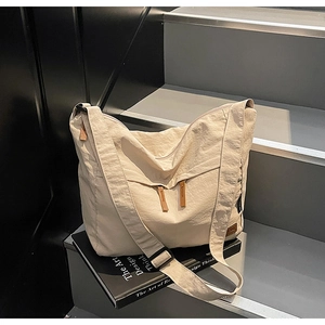 Detail of a large ivory canvas tote bag featuring double front zipper pockets and wide strap