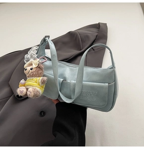 Detail view of light blue pleated faux leather underarm bag with cute bear charm