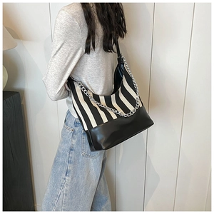 Detail of black and white striped hobo bag with silver chain worn by a model