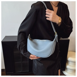 Detail of light blue pebble leather texture on minimalist crescent hobo shoulder bag