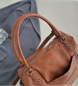 Detail view of brown vintage soft leather handbag with metal zippers and studs