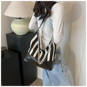 Detailed close-up of striped canvas hobo bag with black leather and silver chain detail