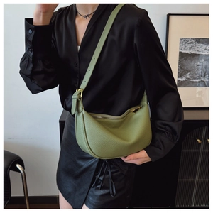 Close-up of grass green crescent hobo bag with litchi texture and golden hardware details