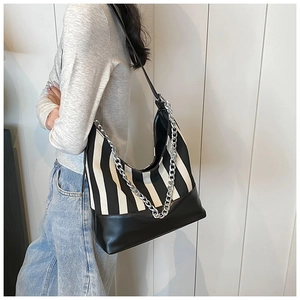 Detail of striped hobo bag featuring canvas patchwork and chunky silver metal chain