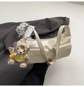 Detail of cream white faux leather bag featuring embossed texture and cute bear pendant