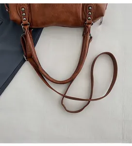 Detail of adjustable shoulder strap and metal rivets on caramel vintage tote bag
