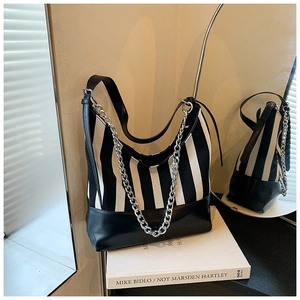 Detail of striped canvas tote with black leather trim and chunky silver metal chain link