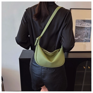 Side view of a light green crescent saddle bag with lychee texture on a model